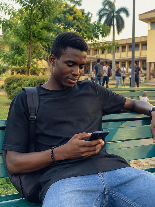 A student scrolling a new social media account on a bench